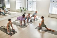 Group of people training on exercise mats together with instructor in class 