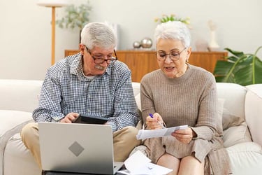Middle aged senior couple sit with laptop