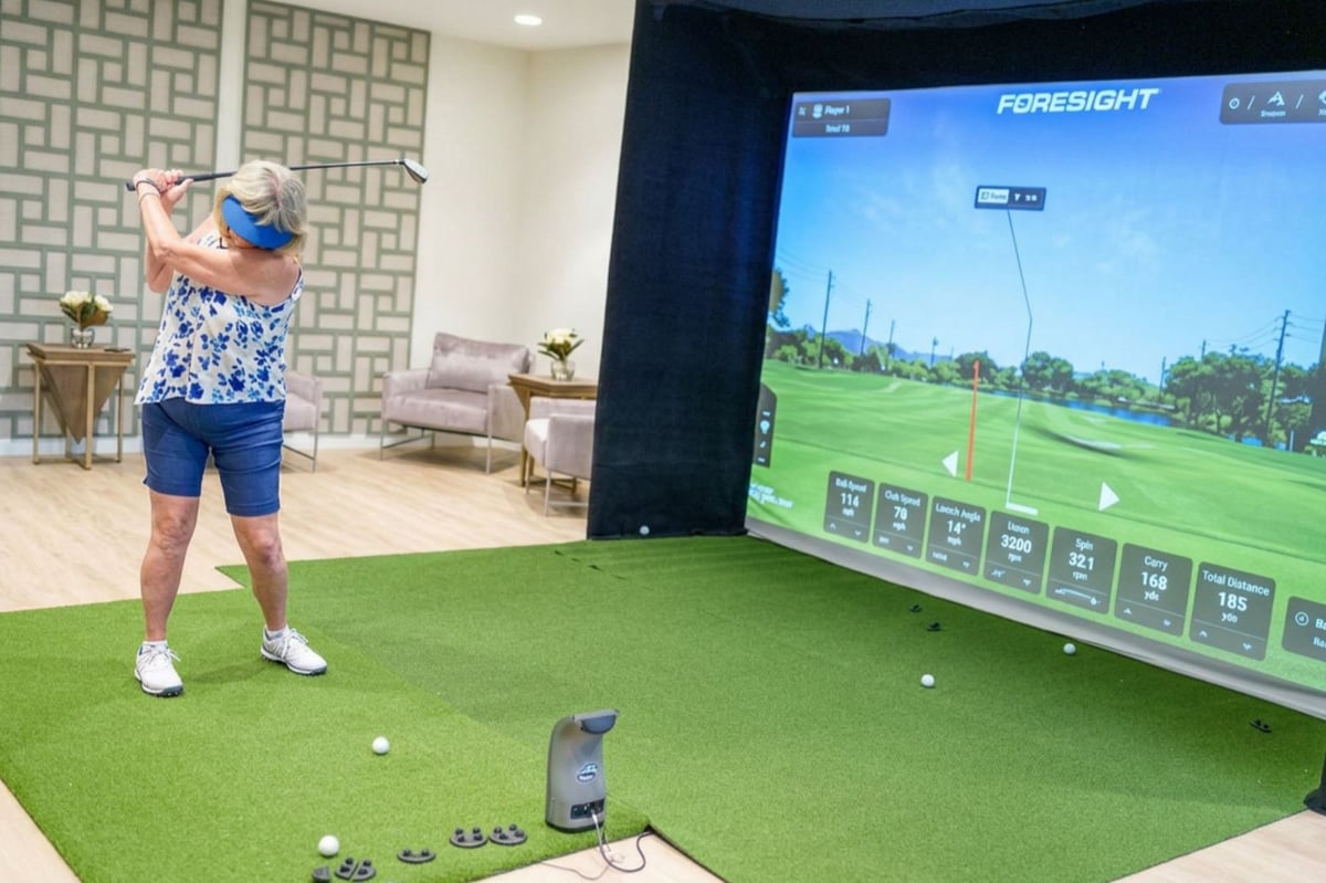 A resident playing the indoor virtual golf simulator at Choreograph Gainesville