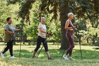 Side view portrait of senior women walking with poles in green park