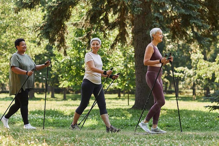 Side view portrait of senior women walking with poles in green park