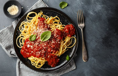 Tasty appetizing spaghetti pasta with tomato sauce served on plate on dark background.