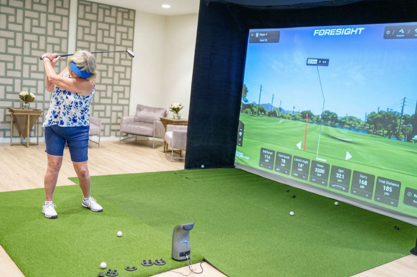 A resident playing the indoor virtual golf simulator at Choreograph Gainesville