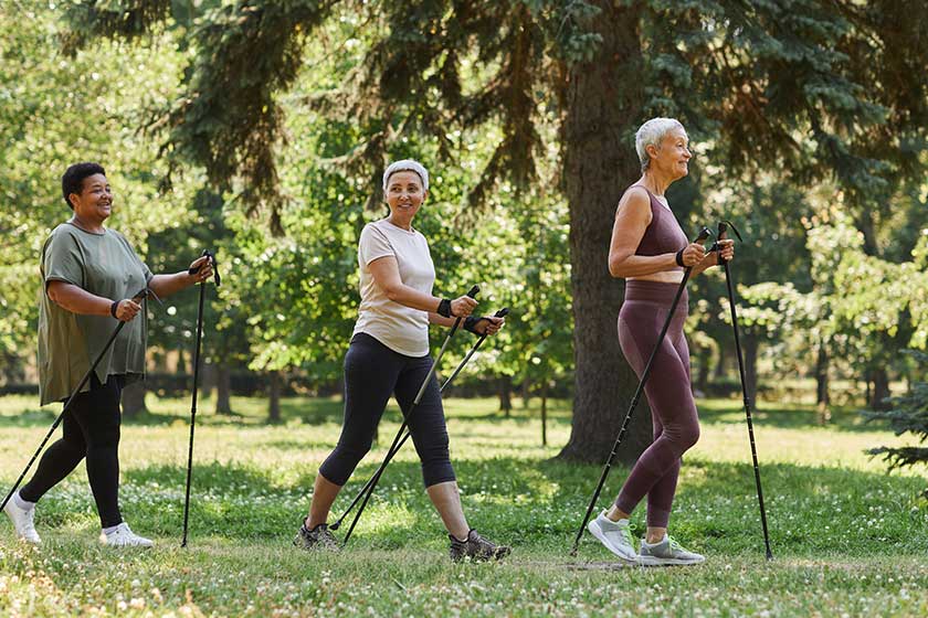 Side view portrait of senior women walking with poles in green park